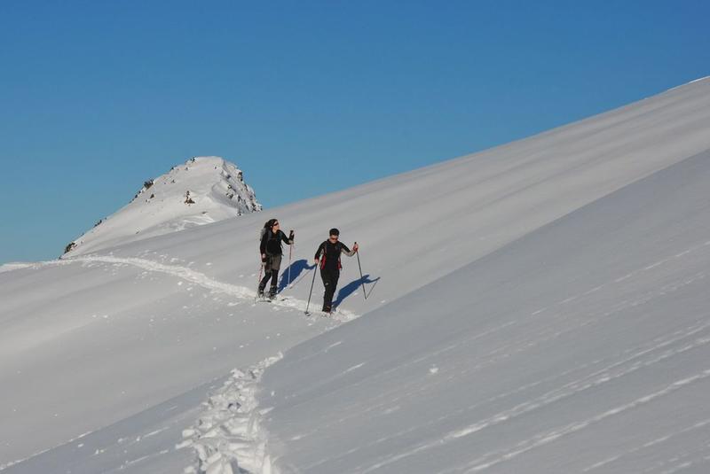 Deux randonneuses à ski dans la trace de montée dans la neige fraîche sous le ciel bleu. Deux randonneuses à ski dans la trace de montée dans la neige fraîche sous le ciel bleu.